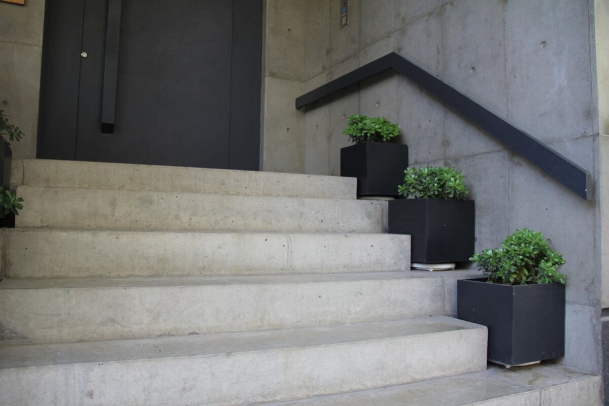 Schody betonowe i drewniane obok siebie w przestronnym holu domu